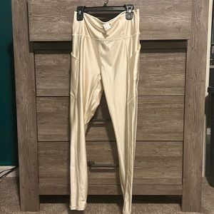 Fabletics cream colored shiny legging with side pockets .